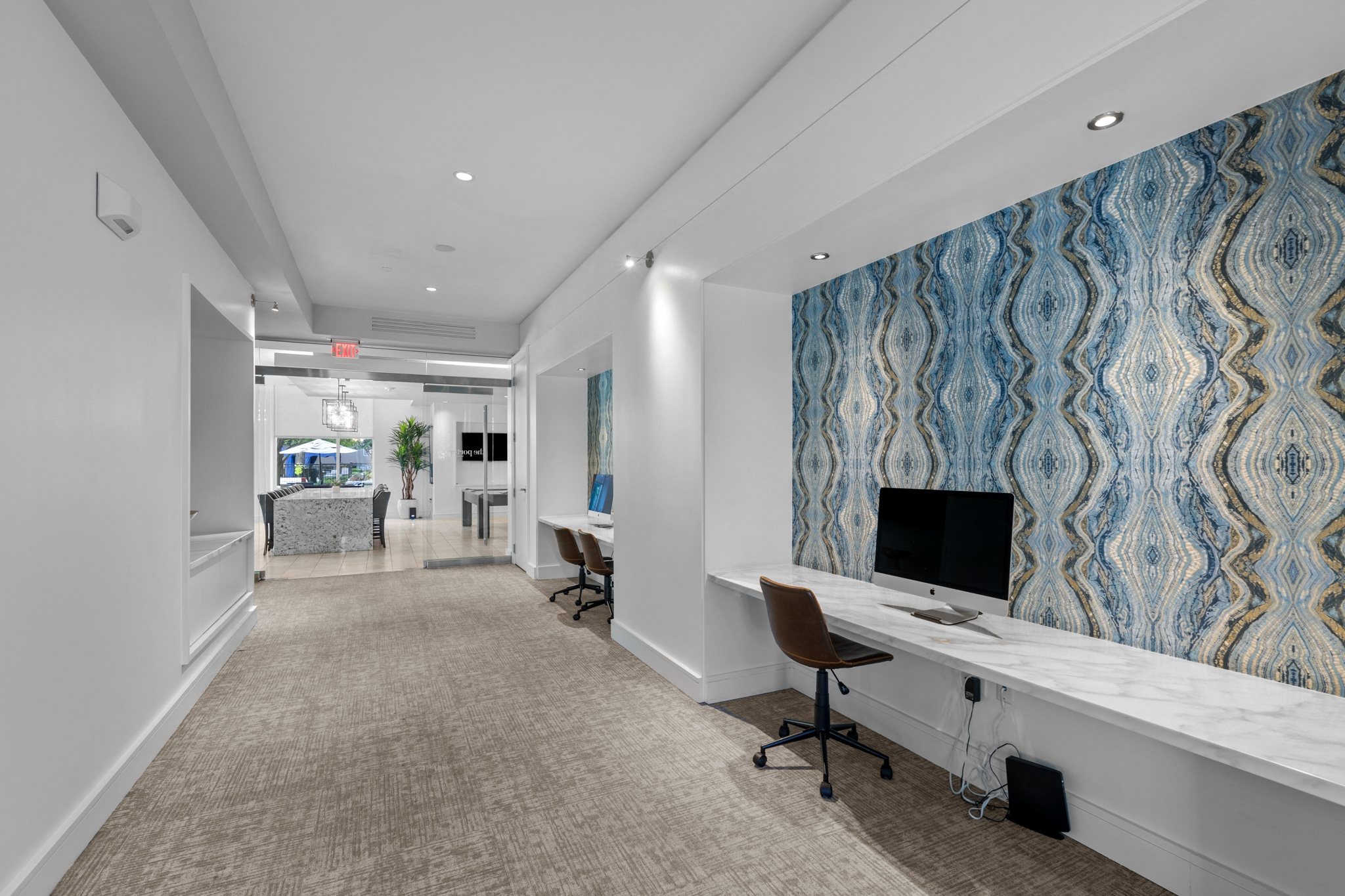 a hallway with a white desk with a computer and a blue and white wall paper